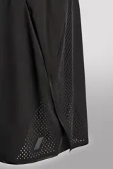 Pantalones cortos negros de tejido técnico perforado, ligeros y elásticos. Cuentan con cintura elástica ajustable con cordón interior, bolsillos frontales, bolsillo trasero de seguridad con cierre de cremallera, perneras con laterales perforados para transpirabilidad, bajo con acabado termofijado y aberturas laterales. Incluye detalle de logo estampado en la pernera.