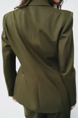 Blazer verde militar entallado con cuello de solapa, manga larga, cierre frontal de un botón y bolsillos con solapa.
