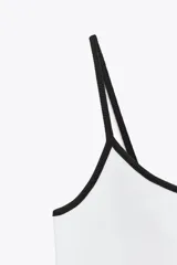 Camiseta de tirantes finos, corte ajustado al cuerpo y escote redondo. El cuerpo es de tejido azul marino jaspeado y el ribete del escote y los tirantes son de color rojo.