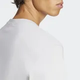 Remera gris claro de corte clásico con cuello redondo y logo Adidas Trifolio estampado en el frente.