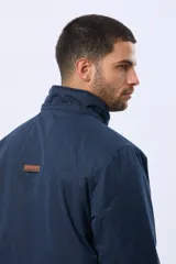 Campera de abrigo color azul marino, con capucha desmontable, cierre frontal con solapa, bolsillos frontales con solapa y detalle de etiqueta de cuero sintético. Cuenta con interior forrado en corderito en la parte superior para mayor calidez.