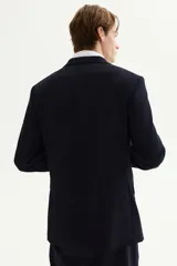 Blazer de hombre color azul marino oscuro, de corte slim fit, con solapas de muesca finas, botonadura sencilla de un botón visible, bolsillo superior insertado y dos bolsillos delanteros con solapa.