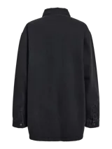 Camisa de denim oversize en color negro lavado, con cuello clásico, mangas largas con puños abotonados y cierre frontal con botones. Presenta un diseño de corte recto y holgado.