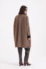 Tapado de textura bouclé en color rojo, con diseño de corte recto, sin cuello y cierre frontal mediante un único botón. Presenta un ribete en contraste de color negro que recorre los bordes de la prenda.