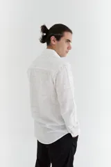 Camisa de manga larga de algodón color blanco con diseño a cuadros finos en negro, cuello italiano, cierre con botones marrones y logo bordado en el pecho.