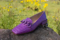 Mocasines color violeta con diseño de cocodrilo y detalle de cadena en el empeine.