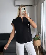 Blusa negra de tela Cey, con cuello mao y escote en V con cierre. Mangas cortas con detalle de encaje marrón en los hombros.