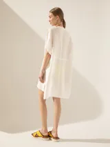 Túnica blanca de lino con corte asimétrico, mangas cortas y escote en V con pespuntes.