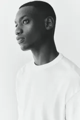 Remera blanca de corte holgado con cuello redondo ribeteado y hombros caídos. Confeccionada con tejido funcional COOLMAX®, una fibra de poliéster de secado rápido que elimina la humedad y regula la temperatura corporal.