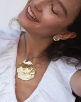 Aros tipo botón dorados con textura irregular que simula la superficie de un molusco.