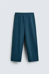 Pantalón jogger de corte relajado y pernera ancha, confeccionado en tejido de algodón con interior perchado. Presenta cintura elástica con cordón interior, bolsillos laterales y un bolsillo trasero de plastrón.