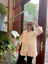 Camisa blanca de broderie con cuello mao, mangas 3/4 con lazo y cierre frontal con botones. Diseño calado con motivos florales.