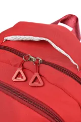 Mochila escolar de tela color azul claro, con múltiples compartimentos con cierre, bolsillo frontal con cierre y un pequeño accesorio colgante cilíndrico a juego. Presenta un parche circular con un emoji sonriente en el frente.