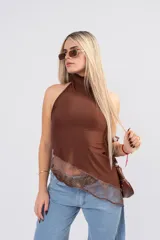 Polera de seda con lycra color blanco, de cuello alto y espalda descubierta. Presenta un diseño asimétrico en la parte inferior con un detalle de encaje sutil en el ruedo.