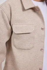 Sobrecamisa de tejido grueso sin forro, con diseño de corte holgado y silueta cuadrada. Presenta cuello clásico, cierre frontal con botones mate y dos bolsillos en el pecho con solapa.