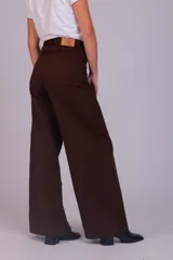 Pantalón de corte wide leg confeccionado en pana acanalada color marrón chocolate. Presenta tiro alto, cierre frontal con botón y bolsillos laterales.