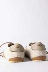 Championes urbanos de gamuza color marrón, con suela de goma en tono crema y cordones jaspeados. Presenta un refuerzo en la puntera y un detalle en cuero beige en el talón.