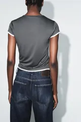 Camiseta de corte slim fit, color verde militar, con cuello redondo y manga corta. Presenta vivos de contraste blancos en el ruedo de las mangas y en el bajo.