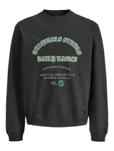 Buzo de manga larga y cuello redondo, color negro, con fit holgado. Presenta un estampado frontal en tonos verde menta y blanco con texto que incluye "Originals Studio", "Daily Basics", "International", "connecting CREATIVITY ACROSS DISTANCES" y "est. 90".