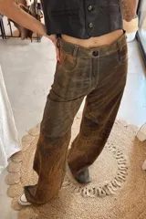 Pantalón de cuero negro, de corte recto y tiro mid-rise, con bolsillos traseros amplios y costuras visibles en las rodillas.