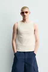 Camiseta sin mangas slim fit color crema, confeccionada en tejido de algodón elástico, con cuello redondo y ribetes en contraste color beige.