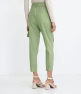 Pantalón carrot de Marfinno en color verde, confeccionado en mezcla de viscosa y lino. Presenta tiro medio, cierre frontal con cremallera, bolsillos, costuras frontales marcadas y detalle de cinturón incorporado con hebilla circular.