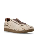 Sneaker de estilo deportivo confeccionado en cuero con pelo, con estampado de manchas tipo vaca en tonos neutros. Presenta cordones de algodón al tono y suela de goma color miel.