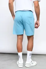 Bermuda deportiva Umbro de color celeste, con cintura elástica con cordón ajustable y el logo de la marca bordado en blanco en la parte inferior de la pierna izquierda.