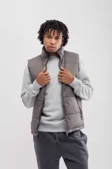 Chaleco puffer color gris topo, con cuello alto y cierre frontal.