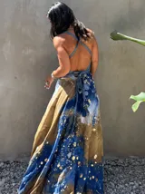 Vestido largo verde con diseño estampado tipo tie-dye y detalles dorados, de corte fluido, un solo hombro y diseño amplio.