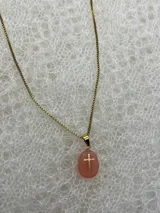 Collar con cadena dorada y dije de piedra natural pulida con cruz dorada incrustada. Disponible en tres colores: rosa, lila y blanco.