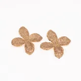 Aros colgantes dorados con forma de flor de cuatro pétalos, cubiertos de strass.