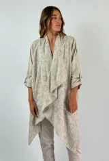 Camisola color beige con calados circulares, mangas 3/4 con trabilla y cuello con solapa.