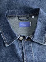 Camisa de manga larga, cuello clásico y fit holgado, confeccionada en tejido de sarga de denim con lavado rinse. Presenta un estampado sutil en la espalda.