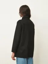 Sobrecamisa negra de corte recto y largo medio, con cuello clásico, cierre frontal de botones y dos bolsillos frontales aplicados.