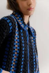 Saco tejido a mano en crochet con diseño de rayas verticales, manga larga y cuello camisero. Presenta cierre frontal con botones y bolsillos delanteros aplicados.