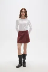 Falda mini de gamuza sintética color bordó, con diseño cruzado y cierre de botón frontal.
