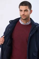 Saco de paño azul marino con capucha desmontable, cierre frontal oculto, bolsillos laterales con tapa y detalles en los puños.