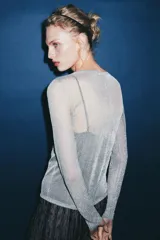 Chaqueta gris de punto fino semitransparente con hilo metalizado, cuello redondo, manga larga y cierre frontal con botones.