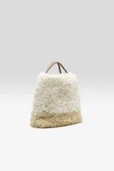 Bolso estilo tote con cuerpo de piel sintética afelpada en color blanco en la parte superior y marrón claro en la base, con asas de mano de cinta marrón.
