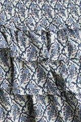 Short pollera mini de viscosa con volados, sección fruncida en la cintura y estampado de patrón ornamental en tonos azules y blancos.