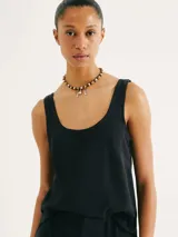 Blusa sin mangas de color negro, con cuello redondo amplio y corte recto, confeccionada en tela fluida.