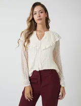 Blusa de encaje color beige, marca Cupio, con cuello a la base y escote en V con lazo de ajuste. Presenta una sobrecapa de encaje con aplique de puntilla y mangas largas de encaje floral translúcido, terminadas en puños elásticos con volado. Incluye forro interno a tono.