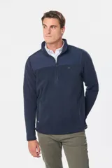 Buzo de micro polar con interior térmico, cuello alto y cierre frontal parcial. Presenta paneles de taslón al tono en el frente y cuello, con bolsillos laterales con cierre y detalle de logo en la manga.