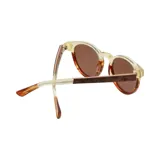 Lentes de sol con armazón de diseño bicolor, combinando una parte superior en tono crema traslúcido y una parte inferior con patrón carey en tonos marrones y naranjas. Cuentan con cristales polarizados de color marrón.
