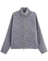 Cardigan de punto gris con cuello alto, cierre frontal de cremallera y doble hilera de botones decorativos metálicos. Diseño de manga larga y corte recto.