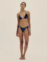 Conjunto de bikini azul marino de terciopelo, compuesto por un corpiño triangular con tirantes finos y una bombacha cavada con lazos laterales.