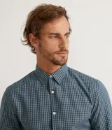 Camisa de corte slim con estampado de cuadros pequeños en tonos azul y verde. Presenta cuello camisero, cierre frontal con botones y mangas largas con puños abotonados.