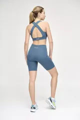 Top deportivo azul con escote redondeado y espalda cruzada.