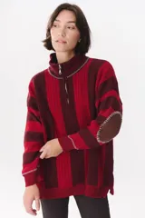 Buzo de tejido de punto con diseño de rayas verticales en tonos bordó y rojo. Presenta cuello alto con cierre frontal, mangas largas con coderas en contraste y detalles de costuras visibles.